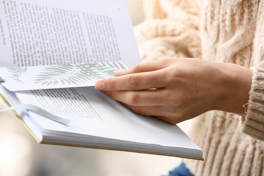 Woman with book and bookmark at home, closeup