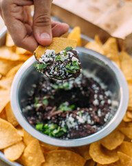 a bite of nacho with mashed black beans with cheese and parsley
