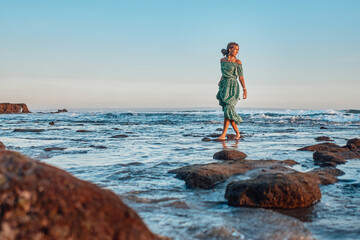 Woman walking on beach in bali at sunset