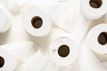 Rolls of toilet paper and feathers on light background