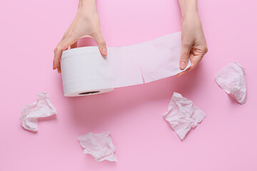 Woman tearing off toilet paper on color background