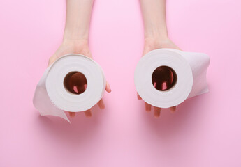 Woman holding rolls of toilet paper on color background