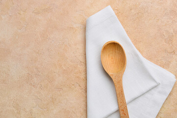 Fabric napkin and wooden spoon on color background