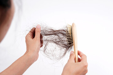A woman's hand grabs the missing hair on the brush, isolated on white background. Hair that has...