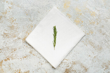 Fabric napkin and rosemary on grunge background