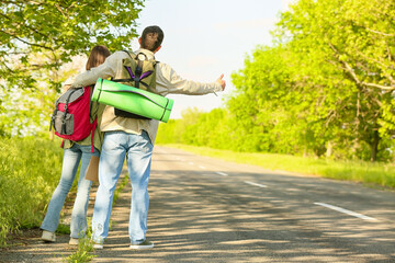 Obraz premium Young couple with backpacks hitchhiking on road