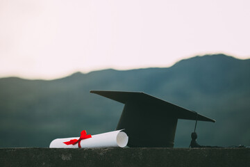 A mortarboard and graduation scroll on the desk with green background.education learning concept