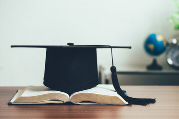 A mortarboard and graduation scroll on open books on the desk.education learning concept