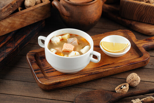Bowl of ukha fish soup with lemon on the wooden background