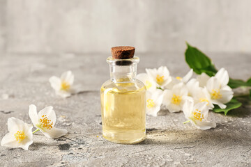 Bottle of essential oil and jasmine flowers on grunge background