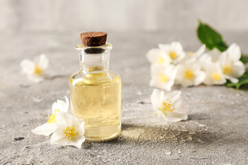 Obraz na płótnie Canvas Bottle of essential oil and jasmine flowers on grunge background