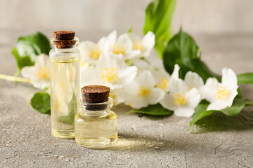 Fototapeta na wymiar Bottles of essential oil and jasmine flowers on grunge background