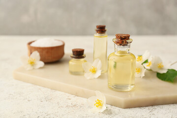 Obraz na płótnie Canvas Bottles of essential oil, sea salt and jasmine flowers on table