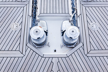 The bow is a teak deck of a luxury yacht, with stainless steel winches, anchor chain attachments...