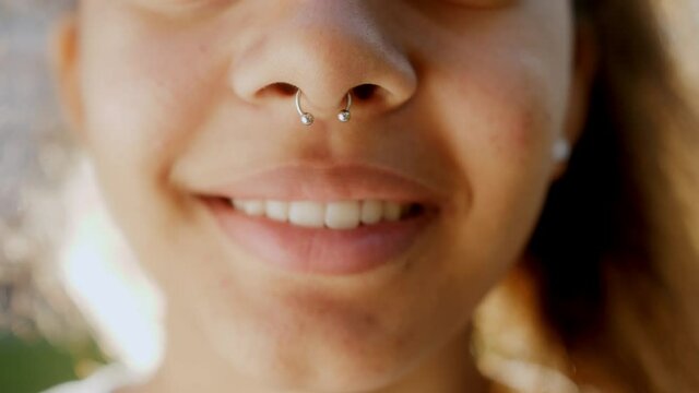Close up of black girl wearing nose septum ring. Close up lips and nose of mixed race young woman. Smiling woman.
