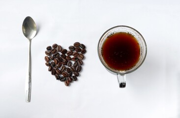 Heart shape made of coffee beans with spoon and coffee cup, spelled i love coffee