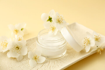 Fototapeta na wymiar Plate with jar of cream and jasmine flowers on color background