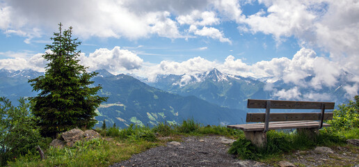 Sitzplatz mit Aussicht- Bank in den Zillertaler Alpen/Tuxer Alpen mit Panoramablick auf schneebedeckte Gipfel, Tirol, Österreich im Sommer - obrazy, fototapety, plakaty