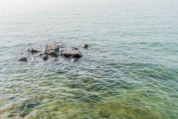 Obraz premium Waves lapping gently against large boulders at surface of water