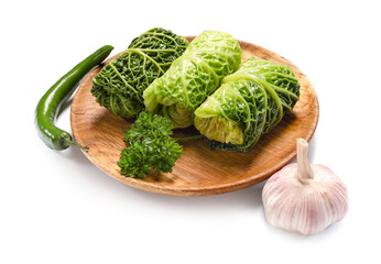 Plate with stuffed cabbage leaves, chili pepper and garlic on white background