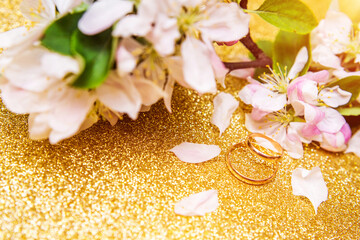 Fototapeta na wymiar Gold wedding rings and Apple blossoms on a Golden background 