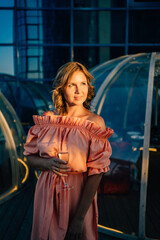 at sunset. beautiful woman in a pink dress on the roof between the igloo tables