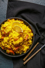 Frying pan with tasty pilaf on dark background