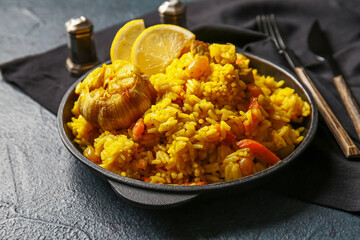 Frying pan with tasty pilaf on dark background