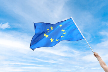 Hand with waving flag of European Union on light background