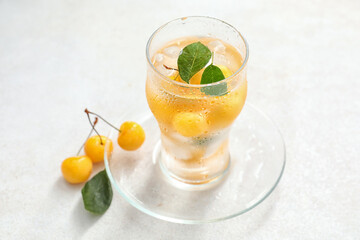 Glass with tasty sweet cherries on light background