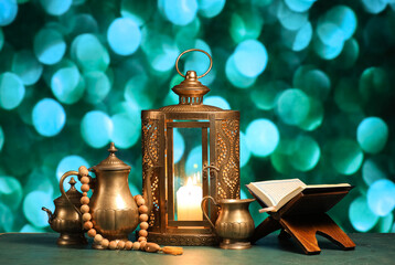 Composition with Koran and lantern on table against blurred lights