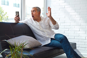 mature man with phone and surprise gesture