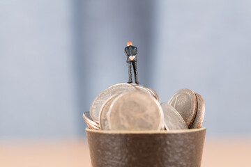 Businessman with full teacup above coins