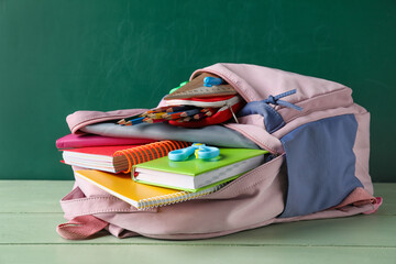 School backpack and stationery on table near blackboard