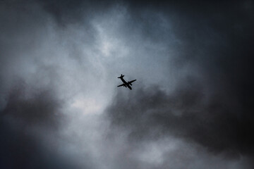 Airplane flying at high speed through storm clouds, small airplane silhouette against dark sky, modern aviation - social media background with copy space