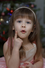 portrait of emotional little girl near christmas tree, thumbs up, idea concept