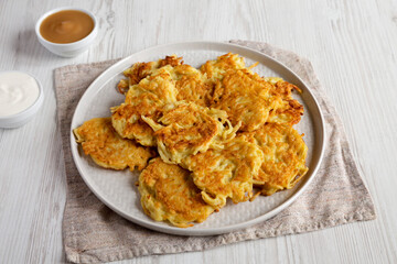 Homemade Potato Pancakes Latkes with Apple Sauce and Sour Cream on a white wooden background, side view.