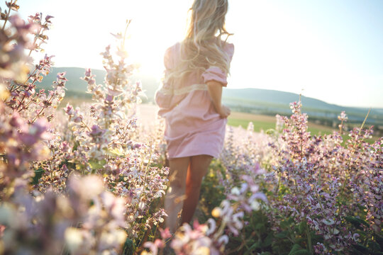 Detail dress in nature. A beautiful girl walks with her back across the field in the evening. High quality photo