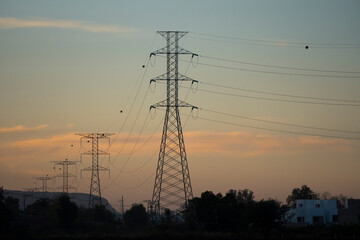 Torres de alta tensi&oacute;n con atardecer al fondo.	