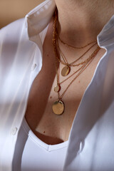 beauty, fashion and jewelry trends concept - close up of woman in white shirt wearing golden multi...