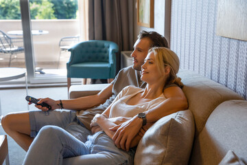 Handsome happy couple watching tv in a hotel room