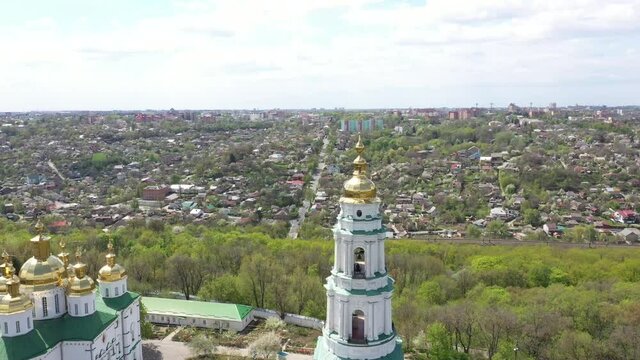 The territory of the church on a hill near the city. High white bell tower and golden domes with a cross