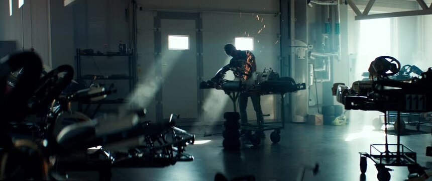 WIDE Mechanic preparing go kart for before a race inside team garage, grinding and fixing parts. 100 FPS slow motion