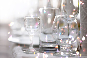 Various glass goblets with bright light from the lenses on the restaurant table.