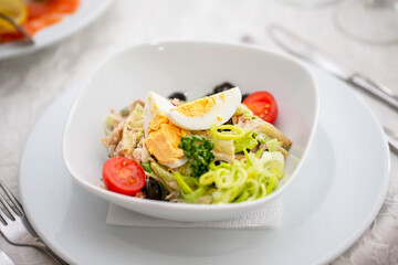 A light appetizer salad of greens, eggs and boiled meat in a small plate on the table.