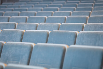 A row of empty blue chairs in the auditorium.