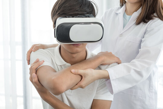 Young Asian men wearing virtual camera technology VR headset glasses Female physiotherapists provide assistance to male patients with elbow injuries examine patients in rehabilitation centers