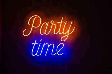 Bright neon lettering: party time., On a dark wall.