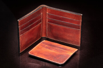 Open leather brown purse with pockets on a dark background.