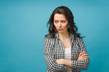 Fototapeta premium Portrait of an angry young woman standing over isolated blue background.